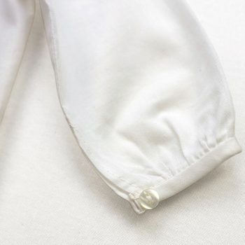 Detalle de la manguita de la camisa de bebé en blanco