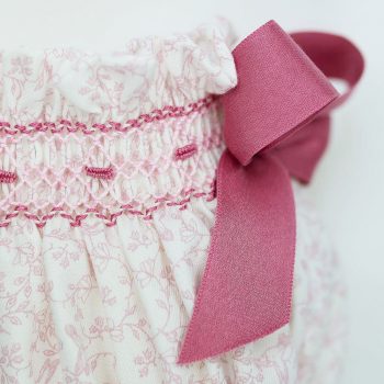 Detalle lateral del cubre pañal bordado a mano y lazada en tonos rosa