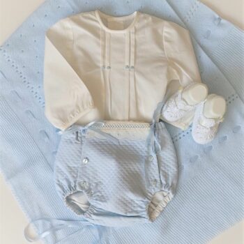 Outfit de bebé compuesto de conjunto blusa bordada a mano con cubre pañal, patucos de ganchillo y toquilla.